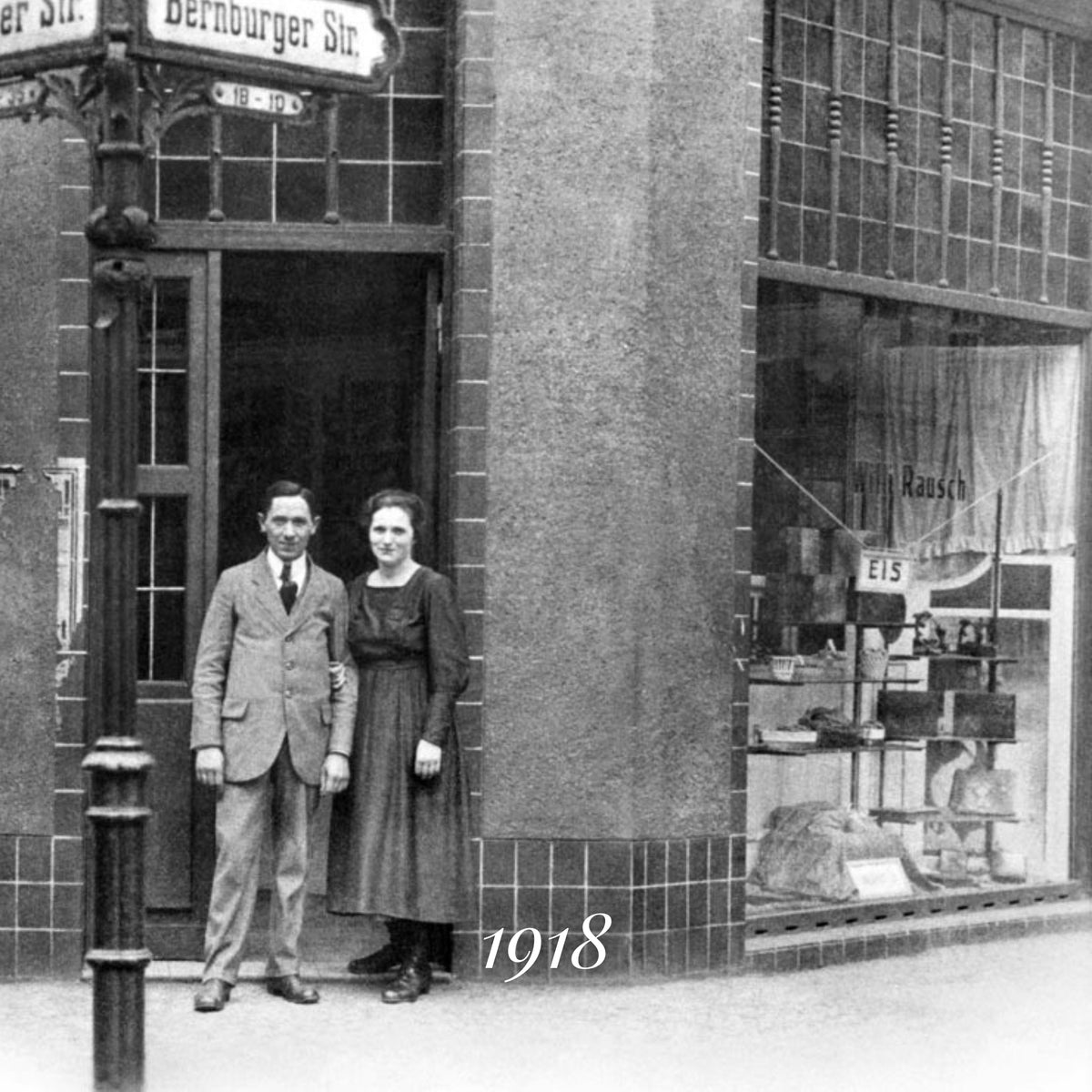 Historisches Foto von zwei Personen in den 1910er Jahren vor einem Schokoladengeschäft in Berlin.