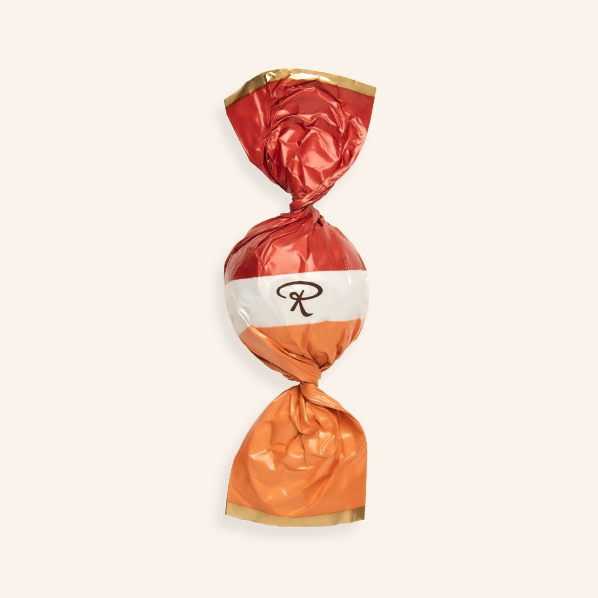In orange Folie eingewickelte Pralinenkugel mit Rausch-Logo auf beigem Hintergrund.