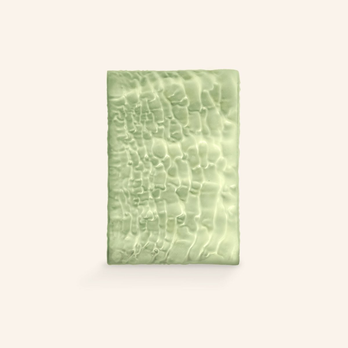 Unverpackte Matcha-Schokoladentafel mit texturierter Oberfläche vor hellem Hintergrund.