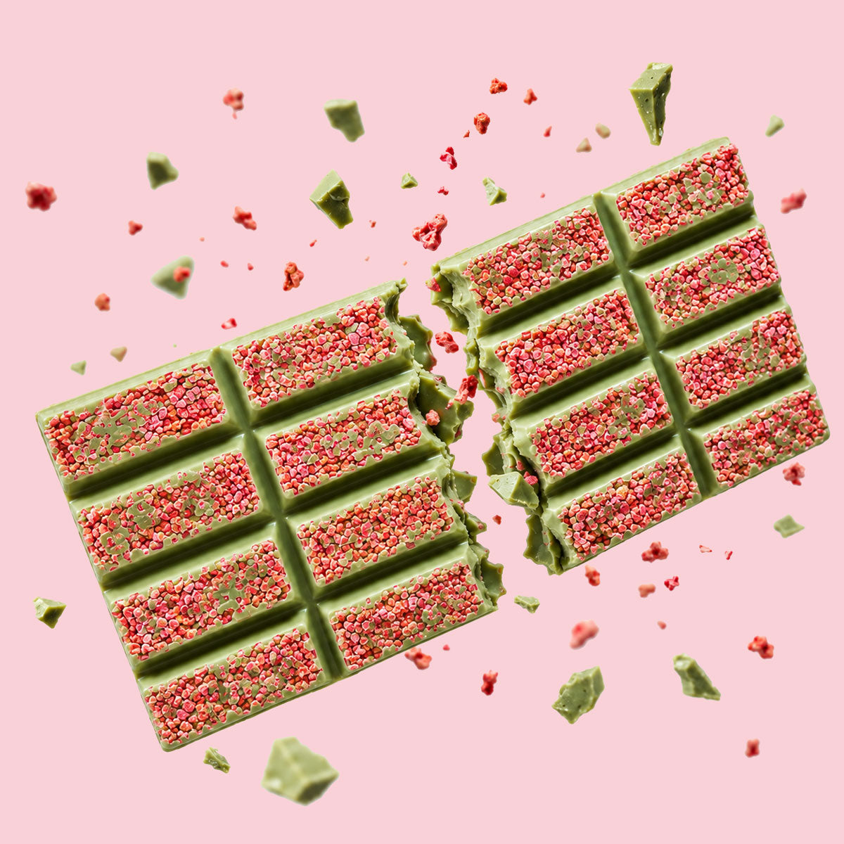 Handwerkliche Schokoladentafel mit grüner Matcha-Schicht und roten Erdbeer-Stückchen auf rosa Hintergrund. - Rausch