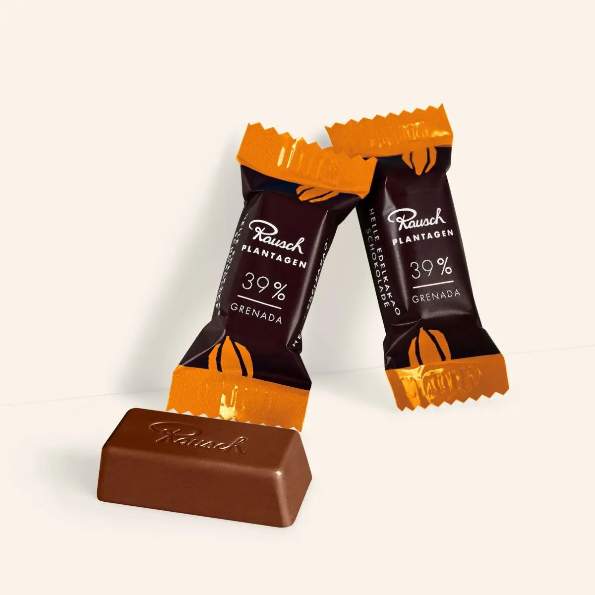 Rausch Grenada 39% Schokolade, zwei verpackte Mini-Tafeln, braun-orange Verpackung, auf hellem Hintergrund.