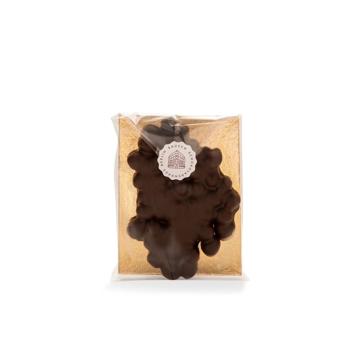 Verpackte dunkelbraune Schokoladenkreation mit Haselnüssen auf goldenem Hintergrund von Rausch.
