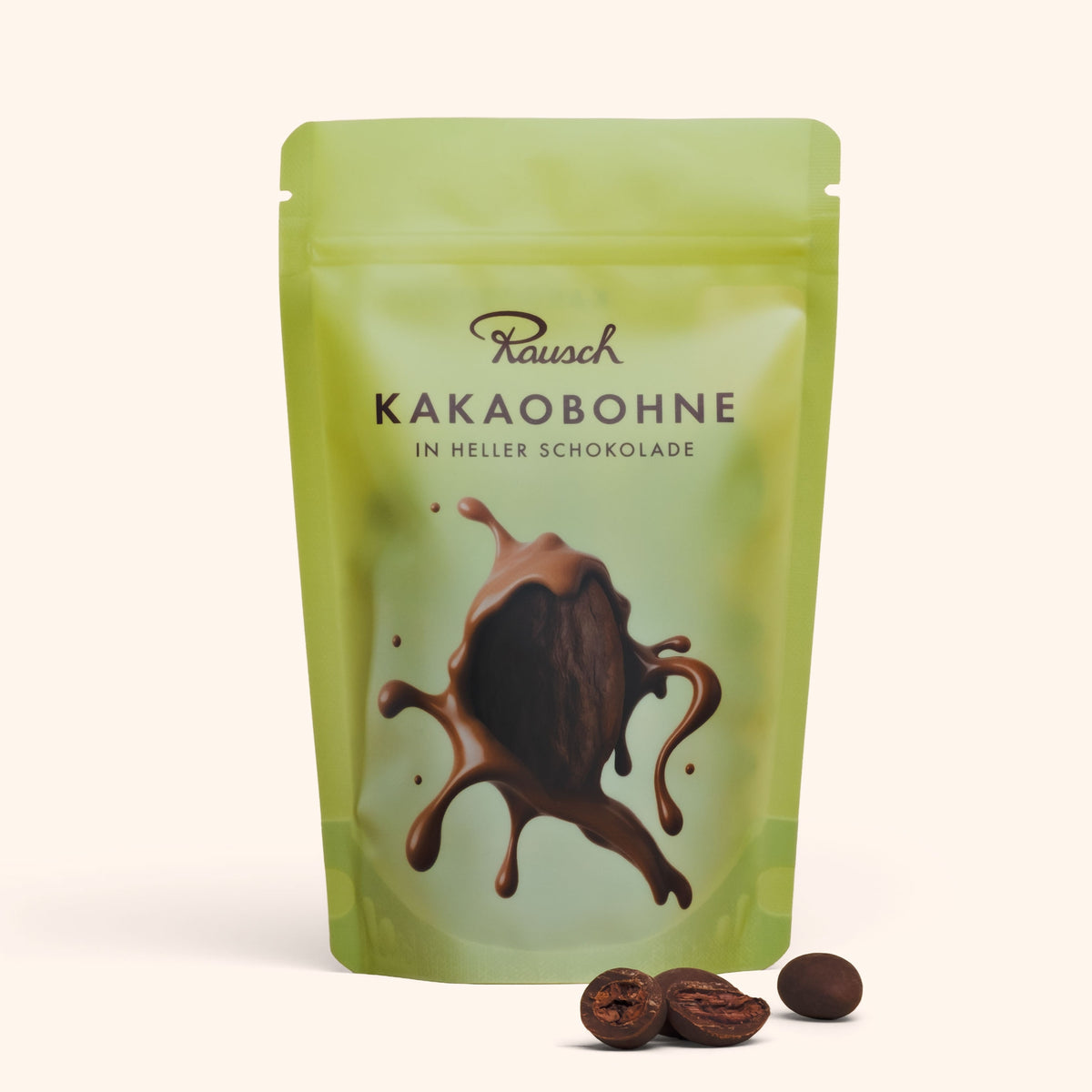Verpackung schokolierter Kakaobohnen in heller Schokolade von Rausch, mit zwei Bohnen davor.
