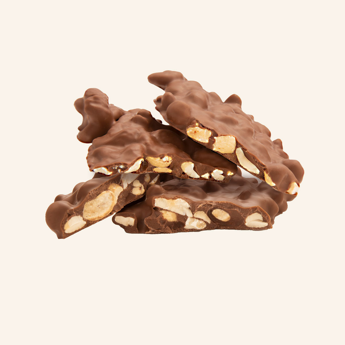 Schokoladenbrüche mit Cashewstücken, ungleich geformt, auf hellem Hintergrund gestapelt.