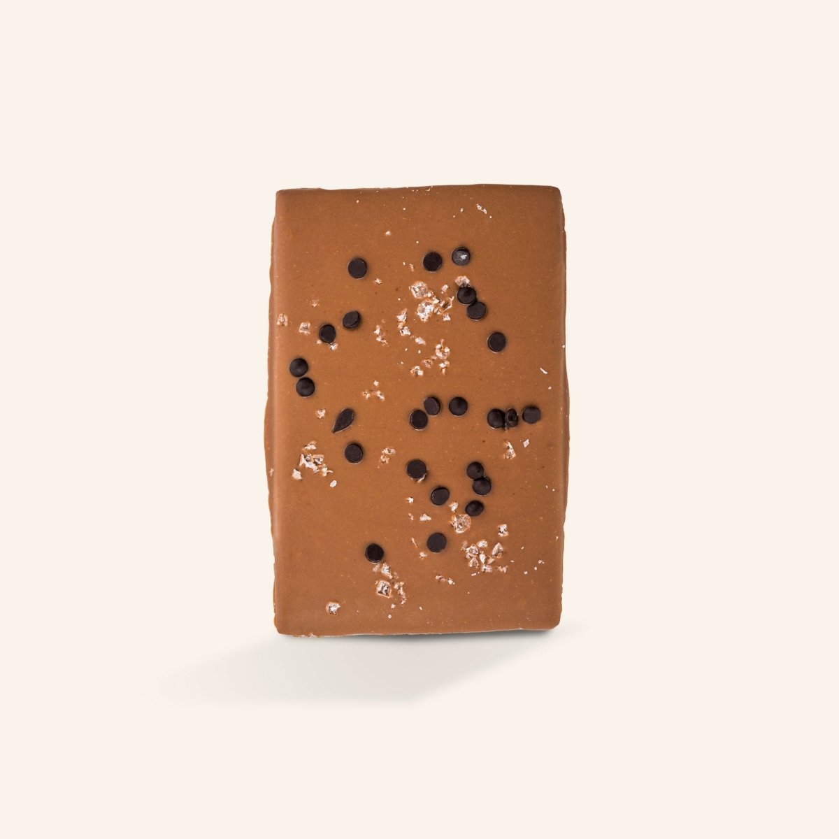 Helle Schokoladentafel mit Meersalz und kleinen Kakaostückchen auf cremefarbenem Hintergrund.