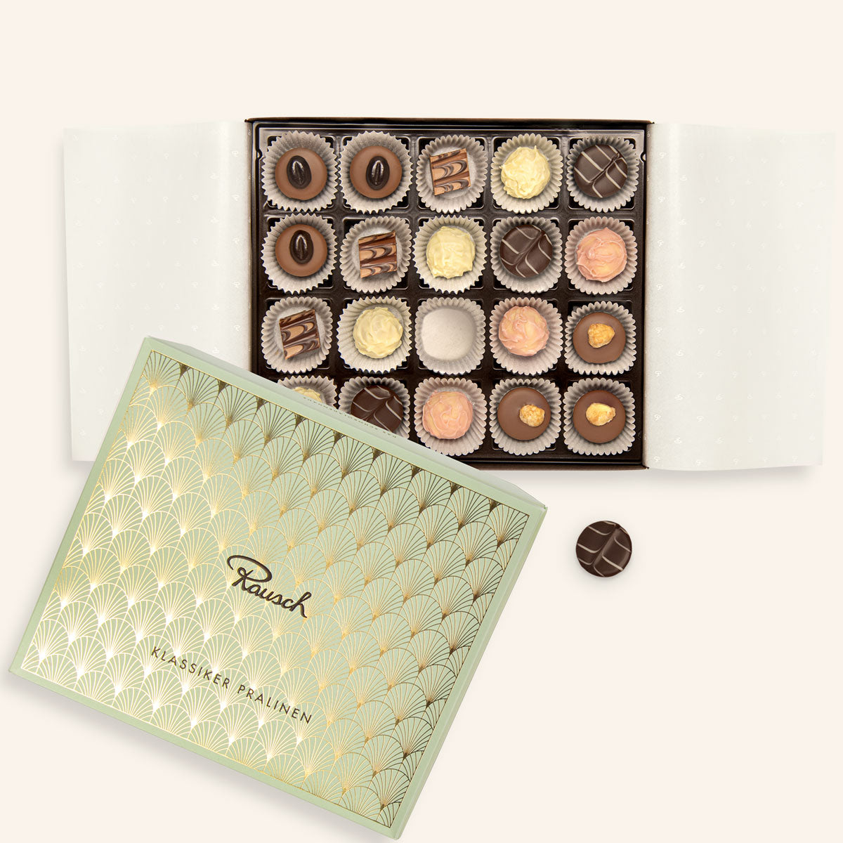 Offene Pralinenschachtel mit 20 gemischten Pralinen, daneben der gold-mintgrüne Deckel mit Rausch-Logo.