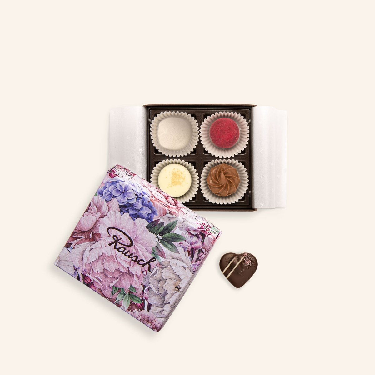 Vier Pralinen in einer floralen Schachtel, daneben eine herzförmige Praline.