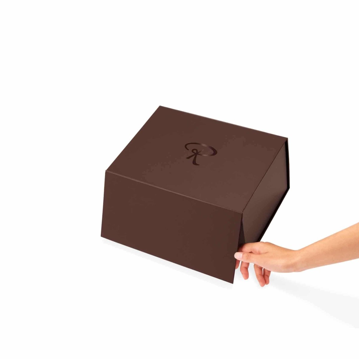 Braune Rausch Geschenkschachtel mit einem Logo, geöffnet von einer Hand, weißer Hintergrund.