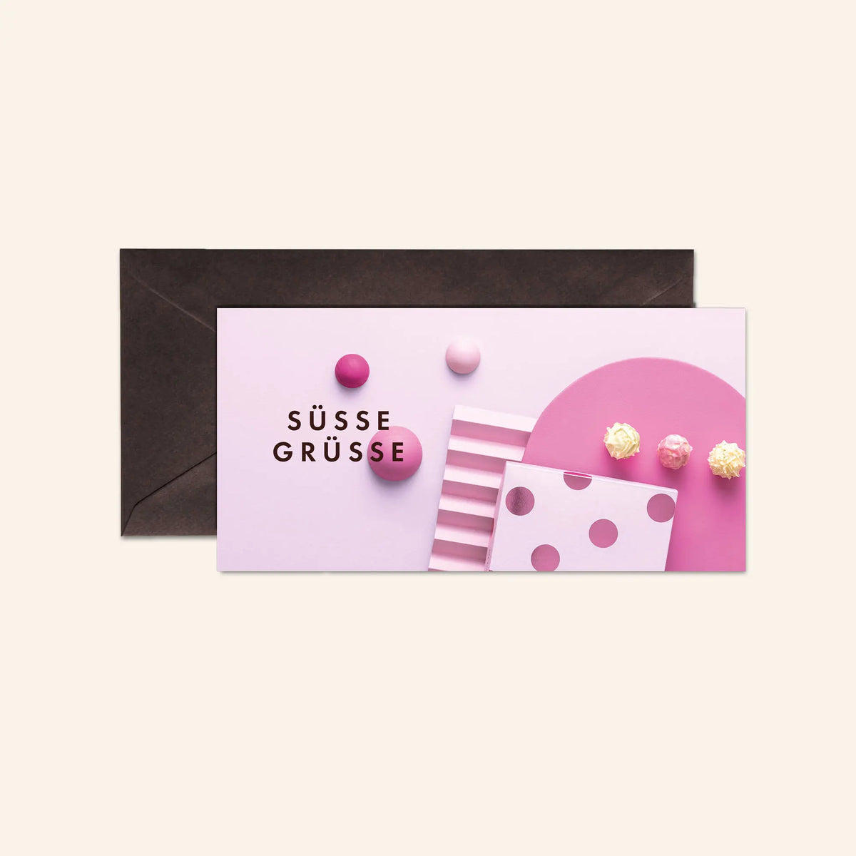 Geschenkverpackung mit "Süße Grüße"-Aufdruck und rosa Dekoration vor einem dunklen Umschlag.