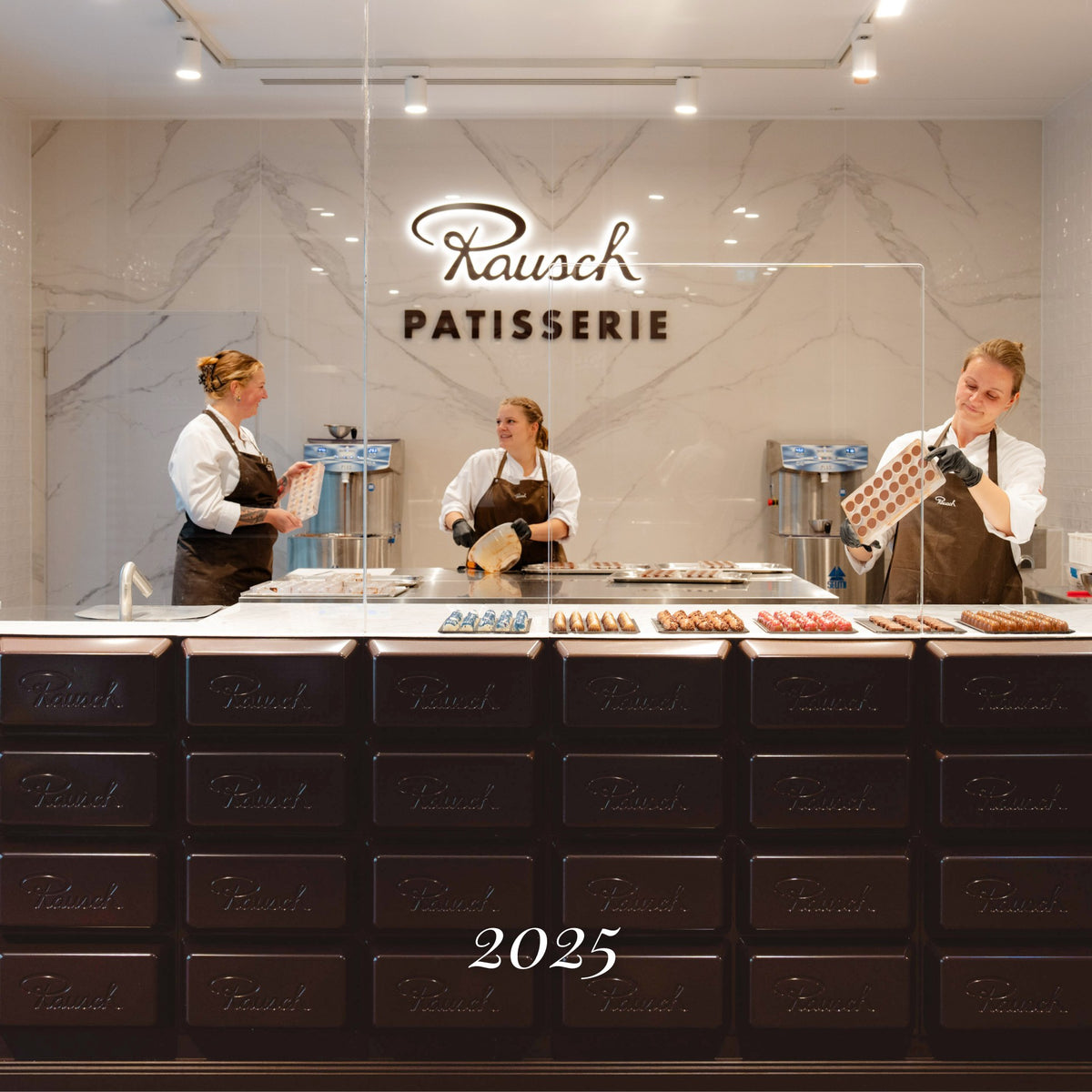 Rausch Patisserie 2025 mit Personal in einheitlicher Arbeitskleidung, die Schokoladenpralinen an einer Theke vorbereiten.