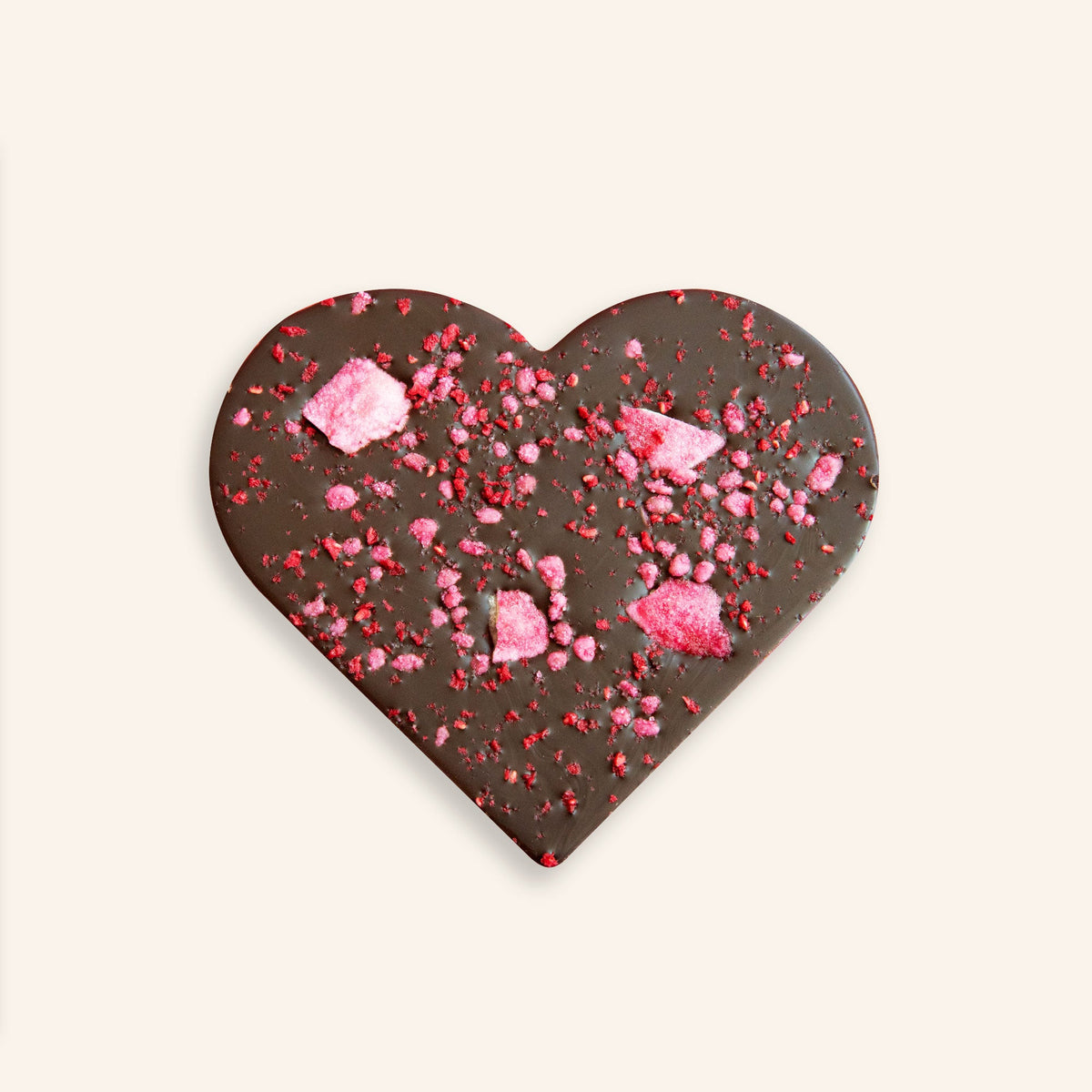 Herzförmige dunkle Schokoladentafel mit getrockneten Rosenblättern und rosa Streuseln, unverpackt.