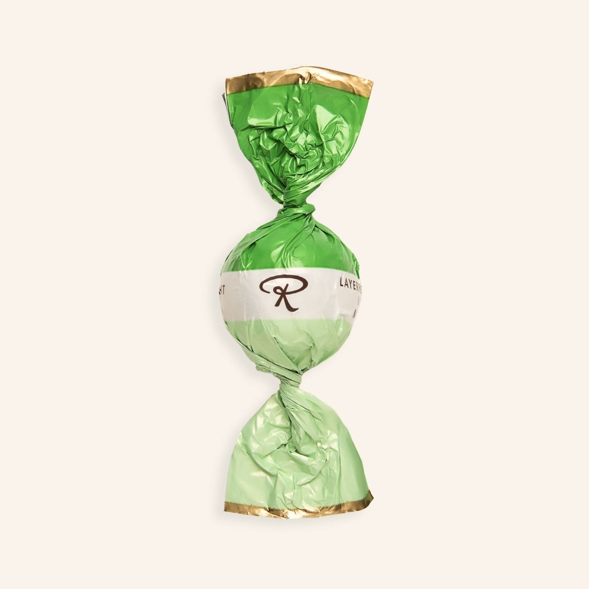 In grüner Folie verpackte Pralinenkugel mit Rausch-Logo auf beigem Hintergrund.