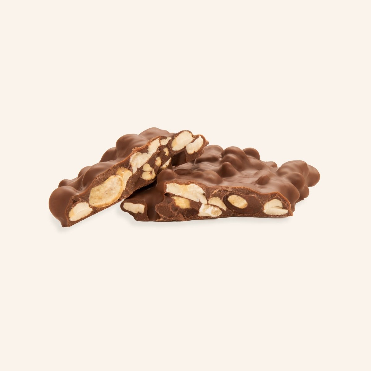 Stück edle Schokolade mit ganzen Cashewkernen, teilweise gebrochen, auf hellem Hintergrund.
