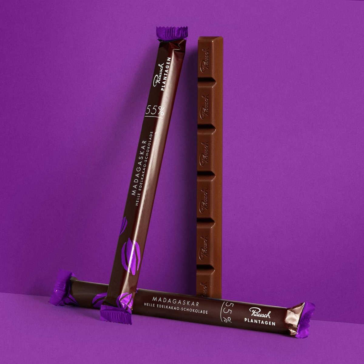 Drei Sticks Madagaskar-Schokolade von Rausch vor violettem Hintergrund, zwei aufrecht stehend.