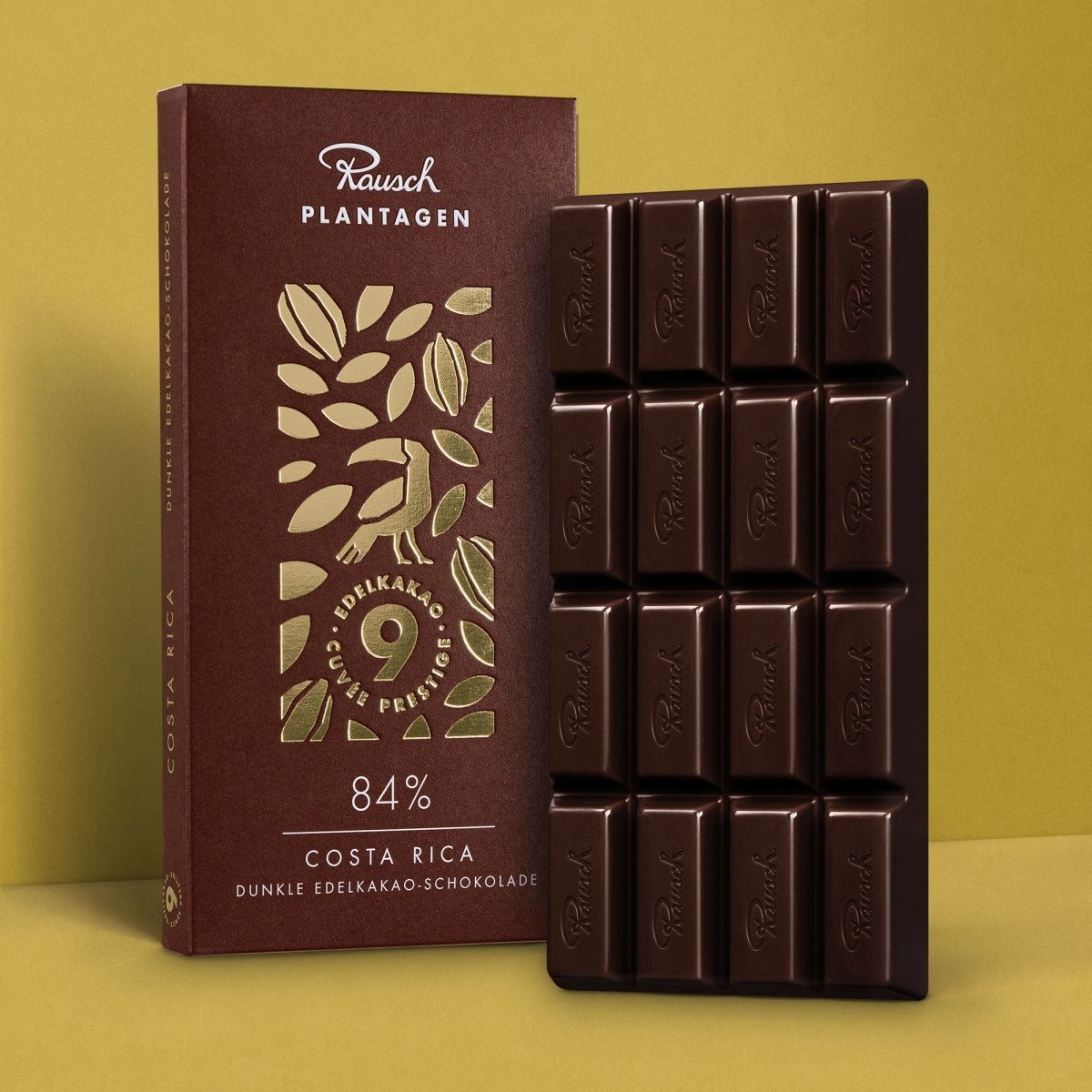 Rausch Costa Rica 84% Dunkle Edelkakao-Schokolade, Tafel und Verpackung auf goldenem Hintergrund.