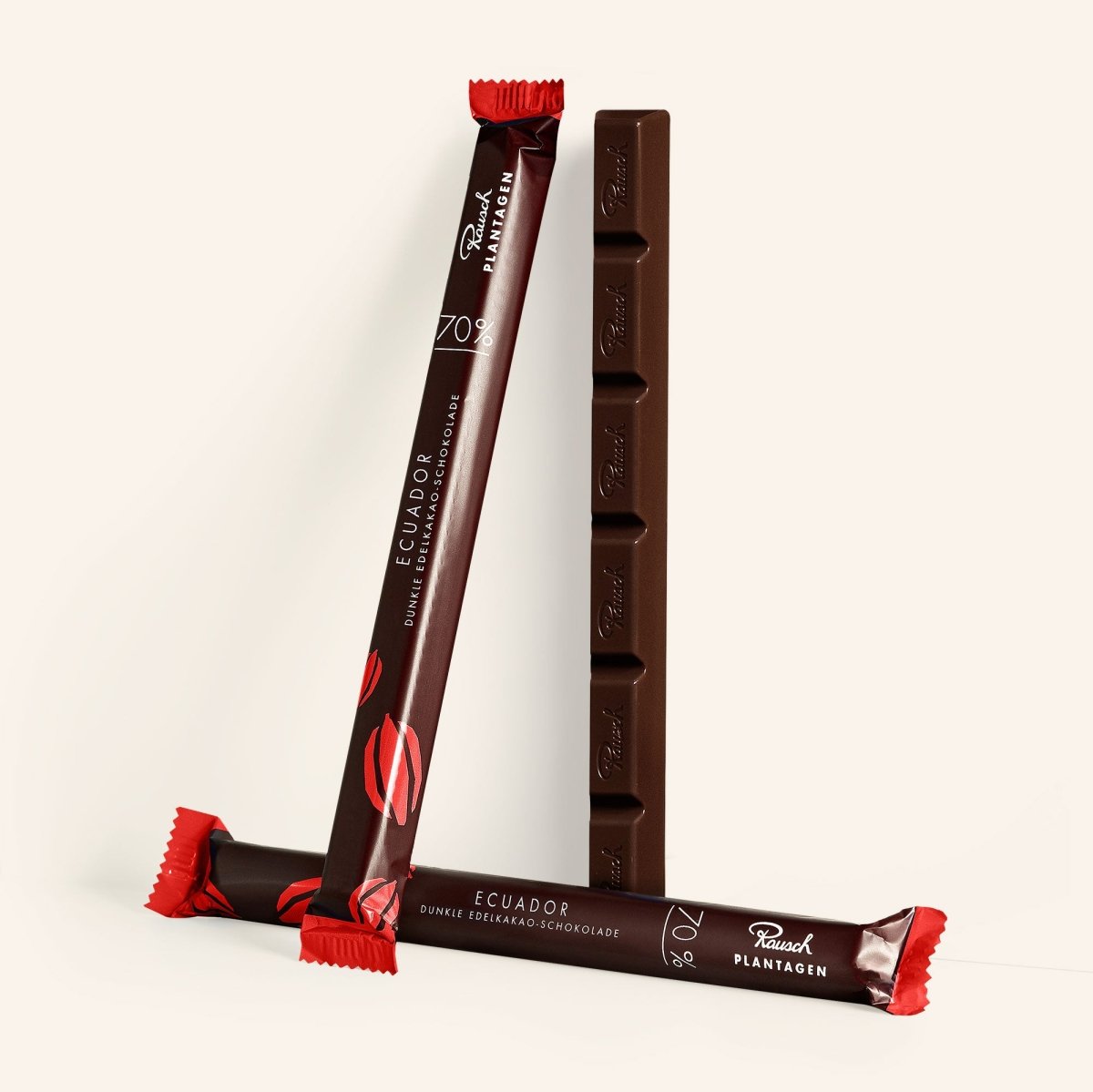 Drei Sticks dunkler Schokolade Ecuador 70% Kakao von Rausch mit eleganter Verpackung in Rot- und Brauntönen.