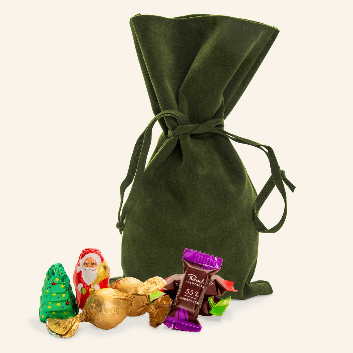 Grünes Samtsäckchen mit weihnachtlichen Schokoladenfiguren von Rausch, darunter Weihnachtsbaum und Schokoladenhase.