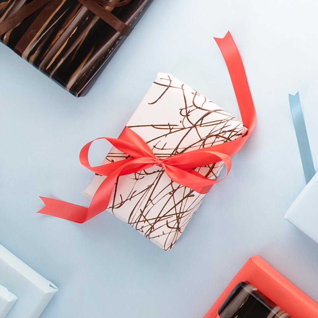 Geschenkschachteln mit roten Schleifen, elegant in hellen Tönen, auf blauem Hintergrund arrangiert.
