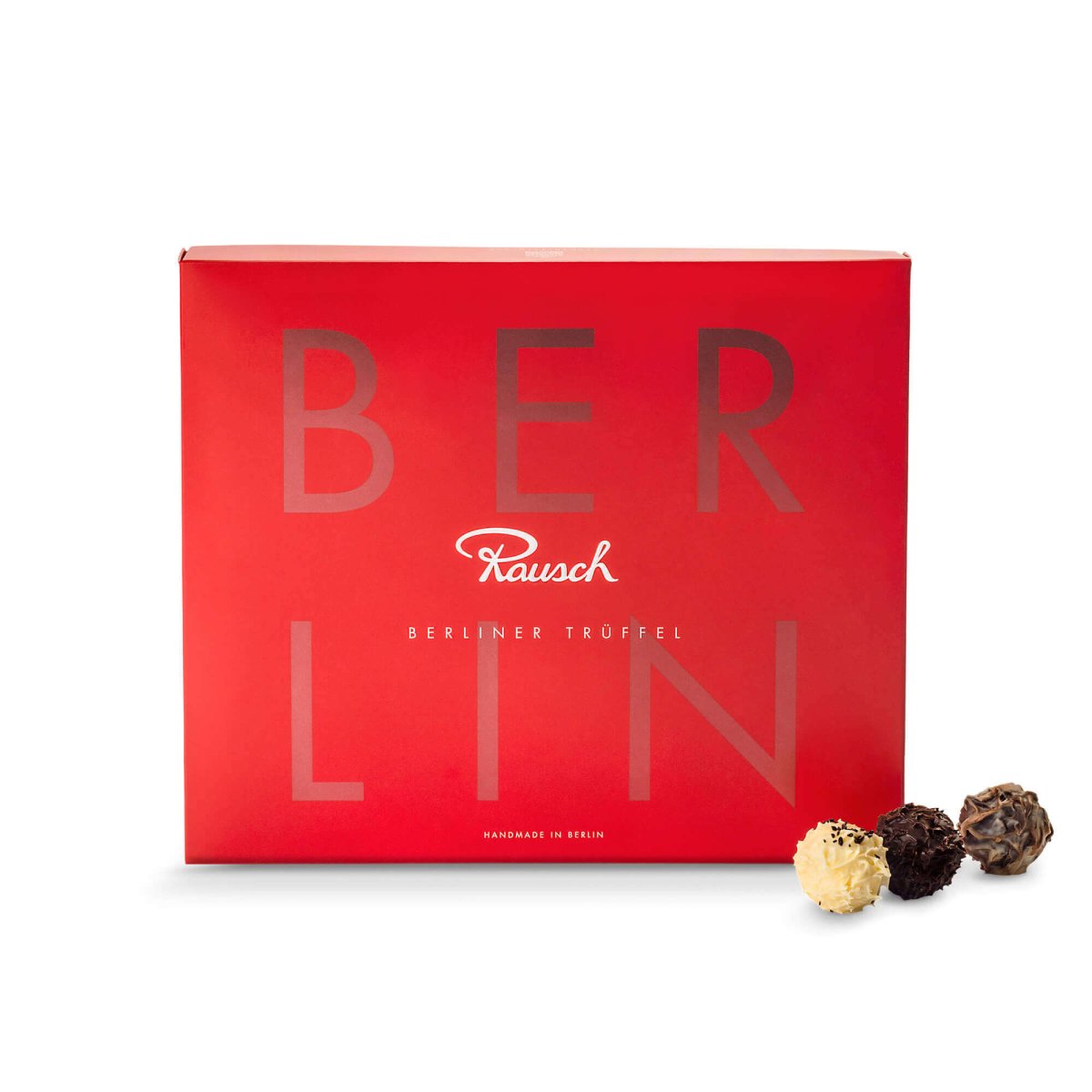Rote Schachtel "Berliner Trüffel" von Rausch mit drei Pralinen davor, stilvoll präsentiert.