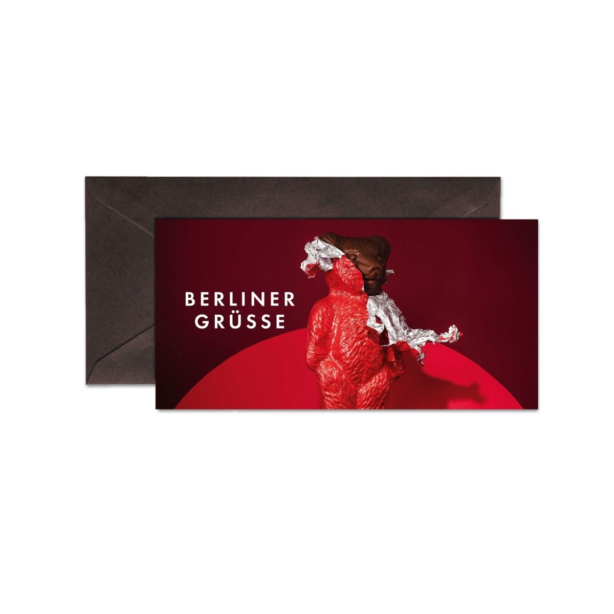 Verpackung der "Berliner Grüße" Pralinen vor dunklem Umschlag auf rotem Hintergrund, von Rausch Schokoladen.