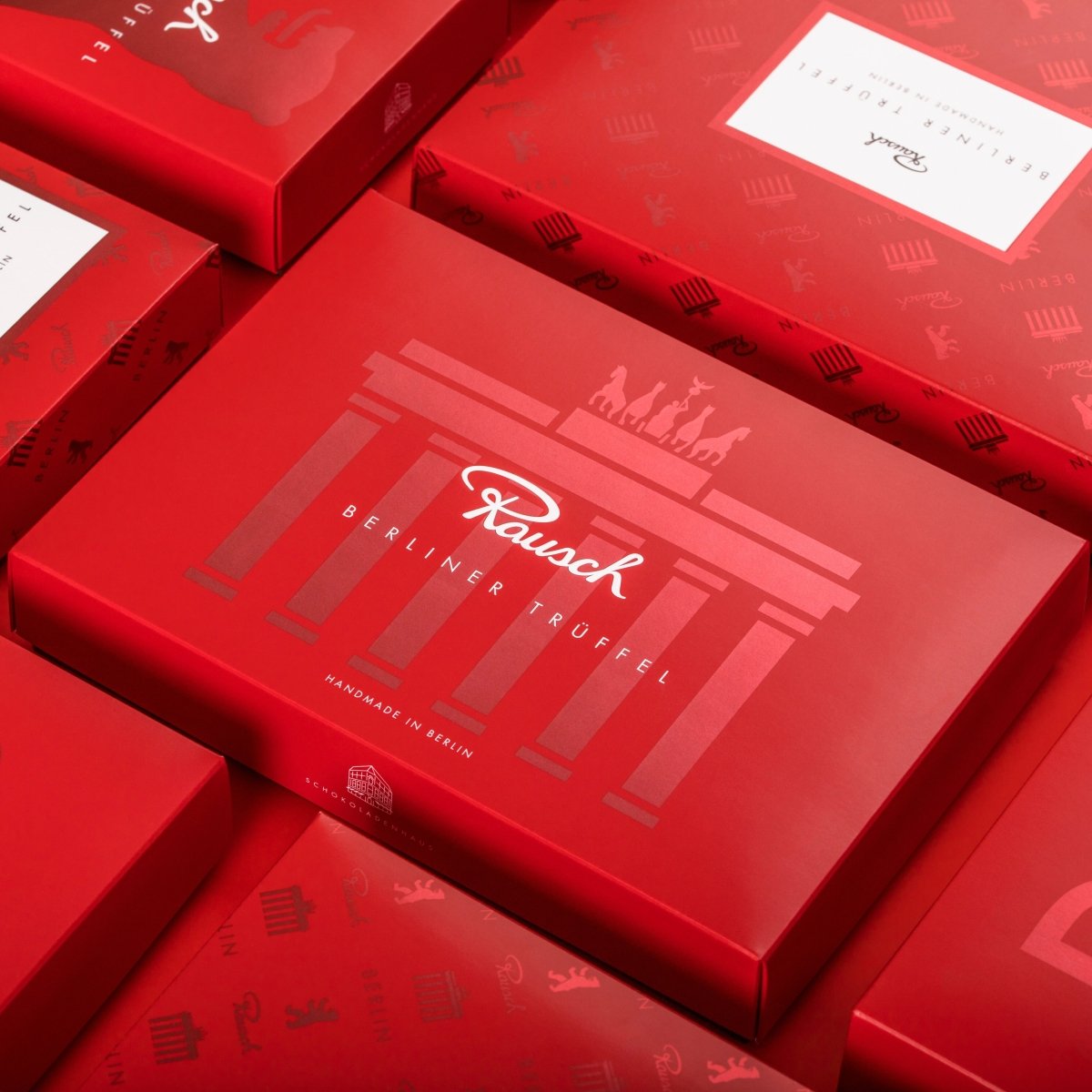 Rote Verpackungen mit Berliner Trüffel-Aufschrift und Brandenburger Tor-Motiv von Rausch.