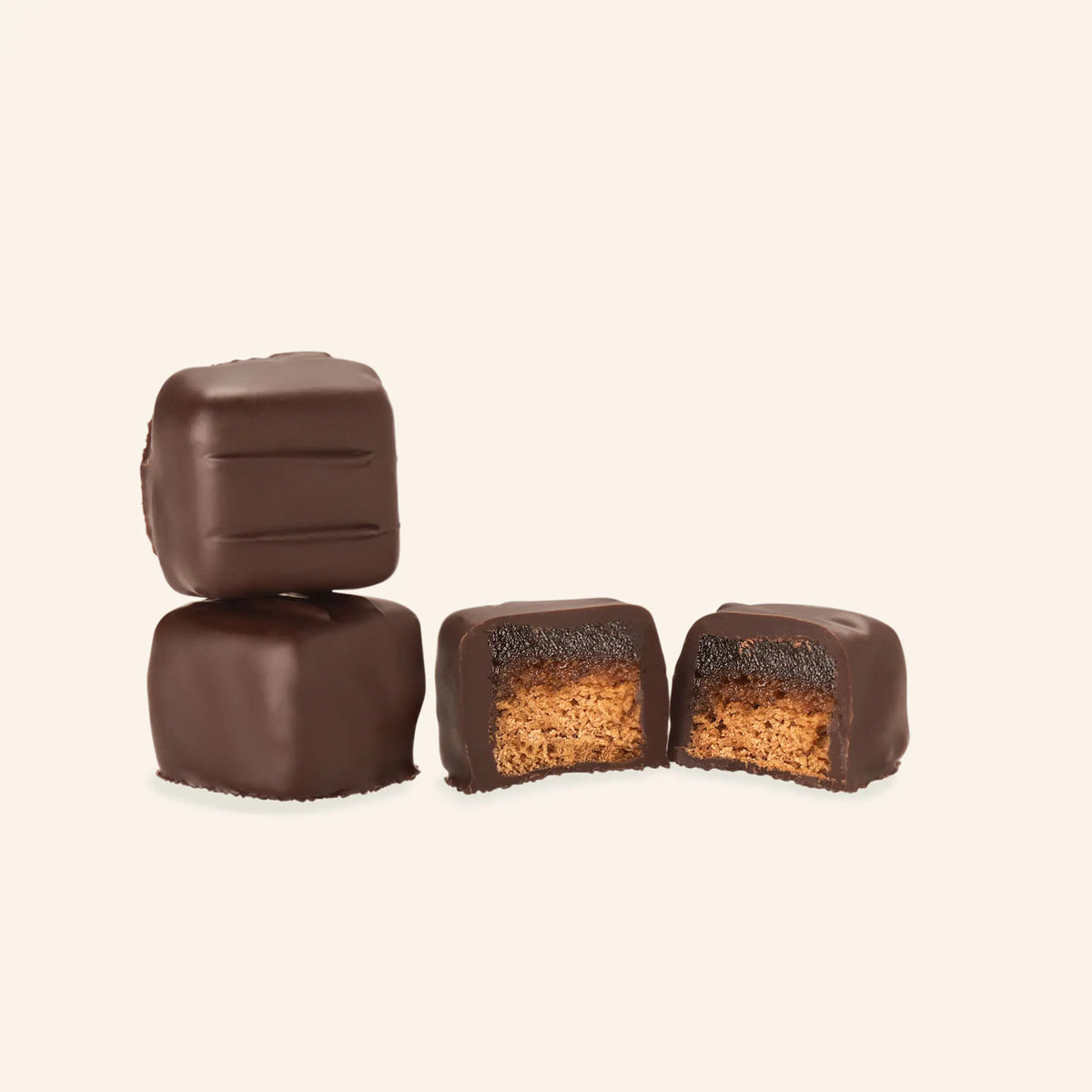 Mehrere Dominosteine mit Schokoladenglasur, einer halbiert, zeigt Fruchtschicht über Lebkuchenboden.