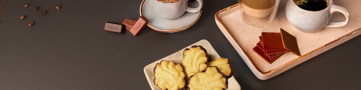 Kaffee und Schokolade mit Gebäck auf dunklem Tisch, elegant arrangiert.