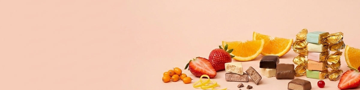 Pralinen mit Erdbeeren, Orangen und Physalis auf hellem Hintergrund.