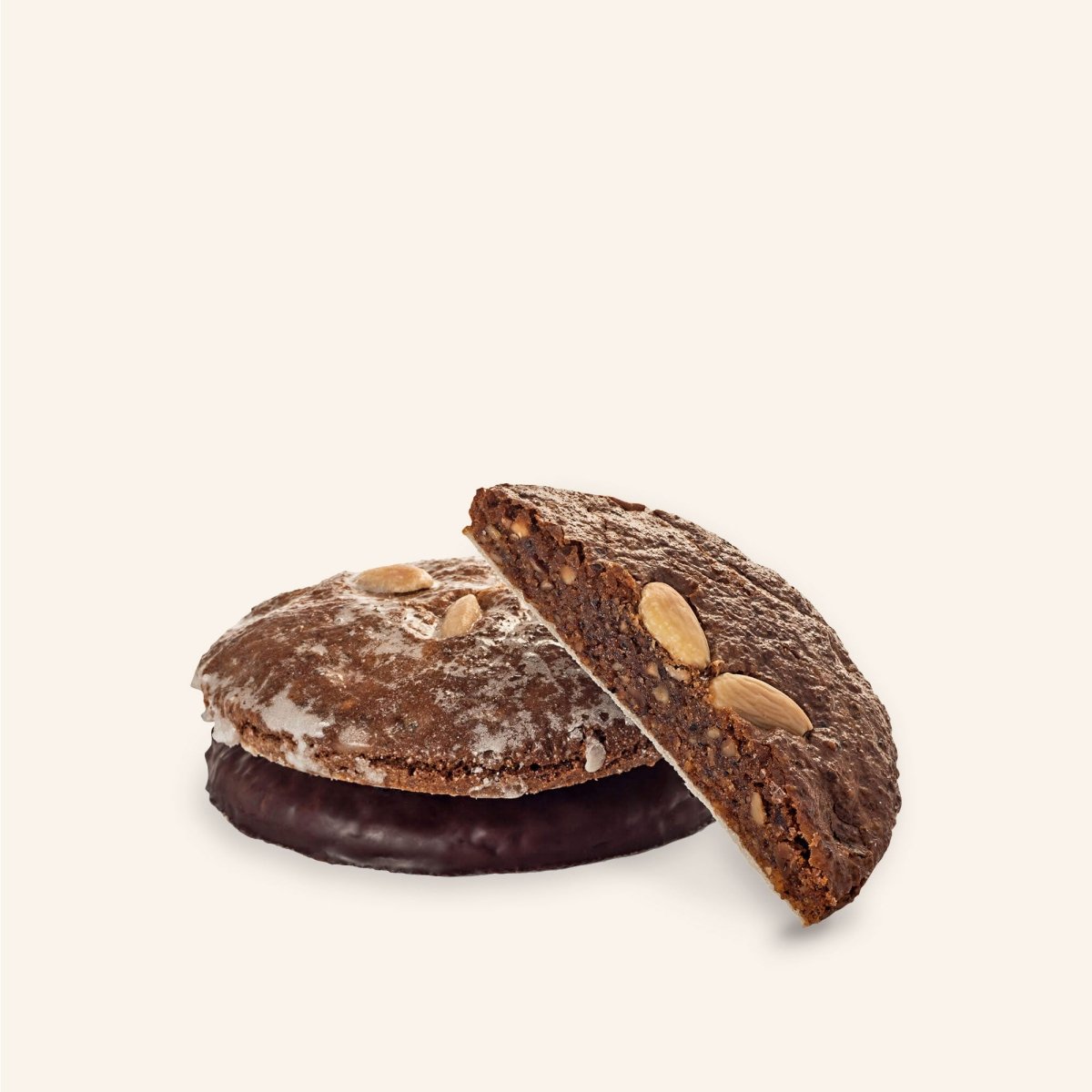 Zwei Lebkuchen, einer mit Schokoglasur, einer ohne, beide mit Mandeldekoration, vor hellem Hintergrund.