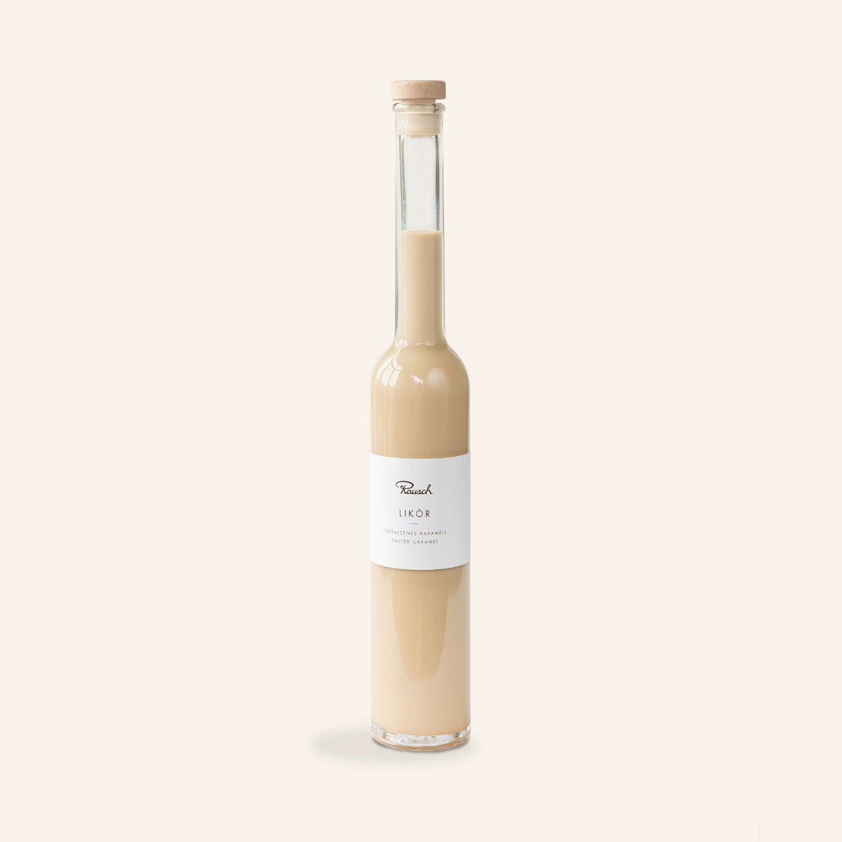 Elegante Flasche mit karamellfarbenem Likör von Rausch, mit schlichtem Etikett auf cremefarbenem Hintergrund.