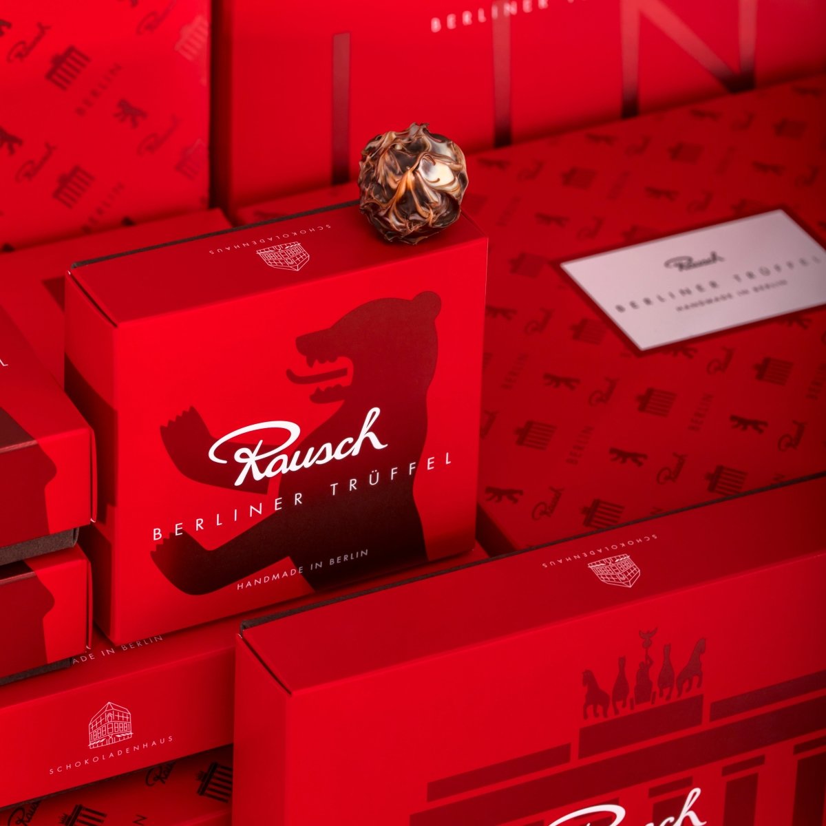Rote Verpackungen von Rausch Berliner Trüffel mit Schokoladenkugel, Berliner Bär Motiv, edel und luxuriös.