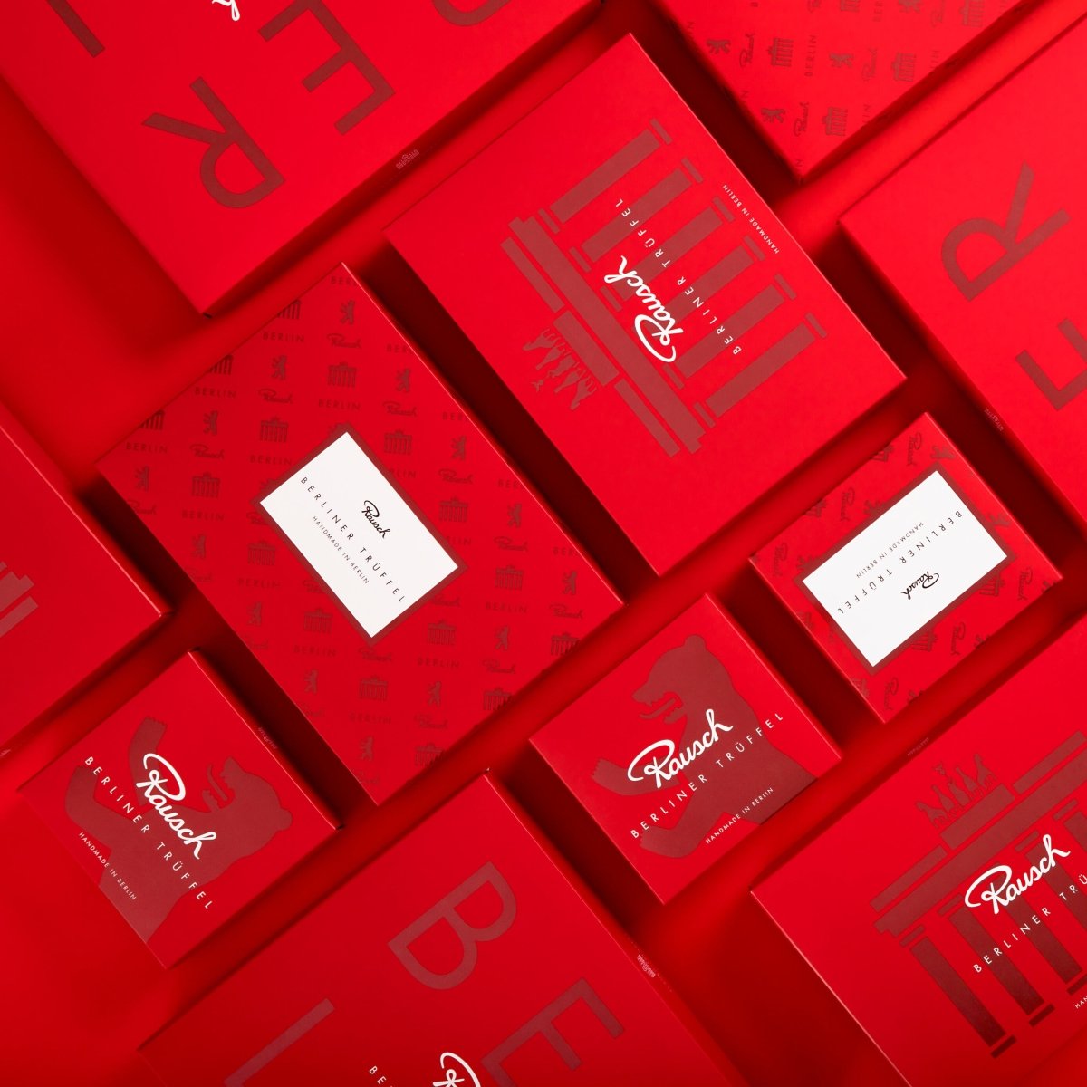 Rote Schokoladenverpackungen von Rausch mit Berliner Trüffeln, teils mit Bär und Krone verziert.