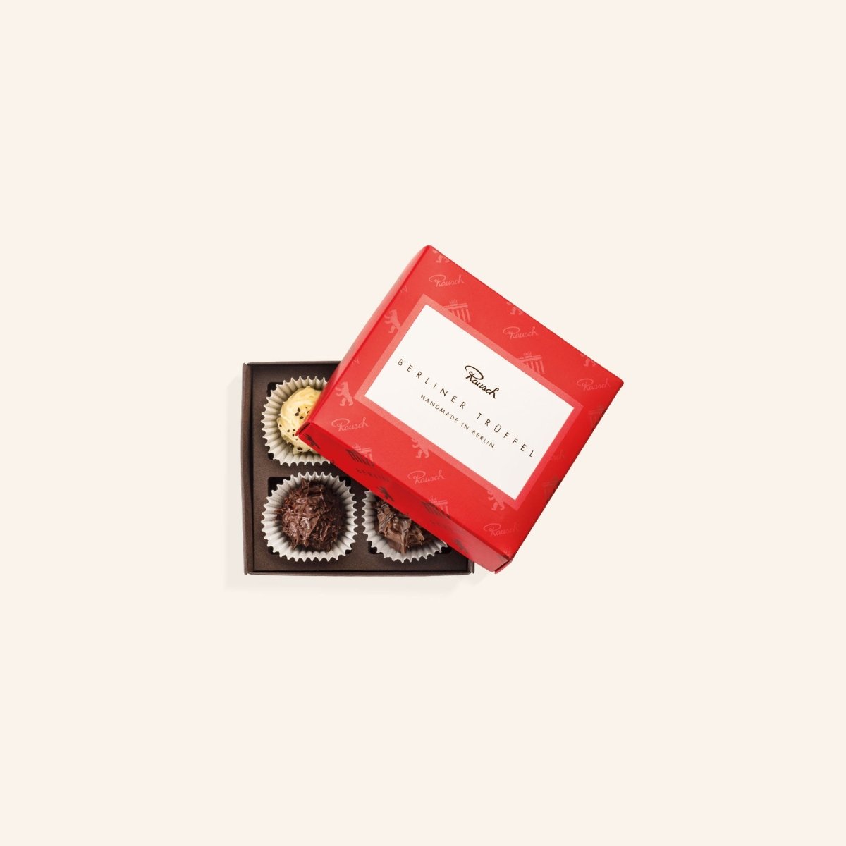 Geöffnete rot verpackte Schachtel mit vier Berliner Trüffeln in verschiedenen Geschmacksrichtungen.