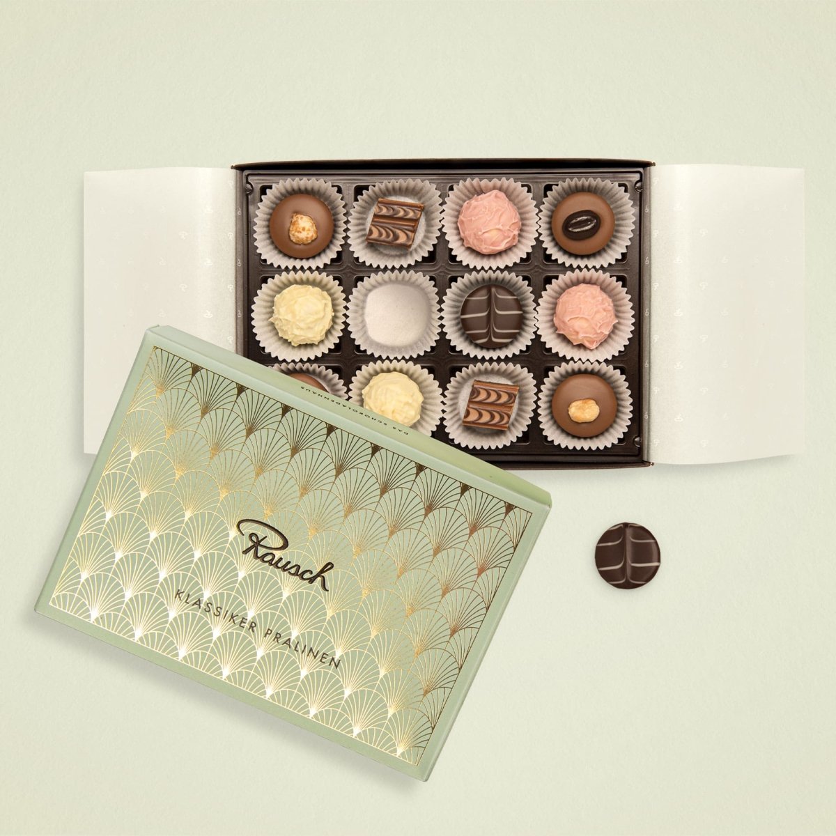 Elegante Pralinenbox mit 12 handgefertigten Schokoladenspezialitäten, offen präsentiert auf hellem Hintergrund.
