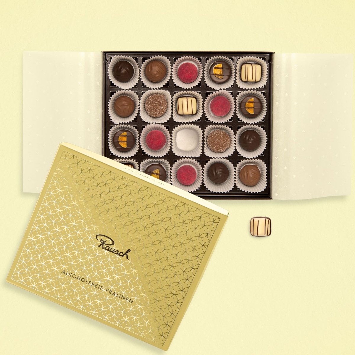 Gelbe Pralinenbox geöffnet, 20 alkoholfreie Pralinen in verschiedenen Designs und Farben sichtbar.