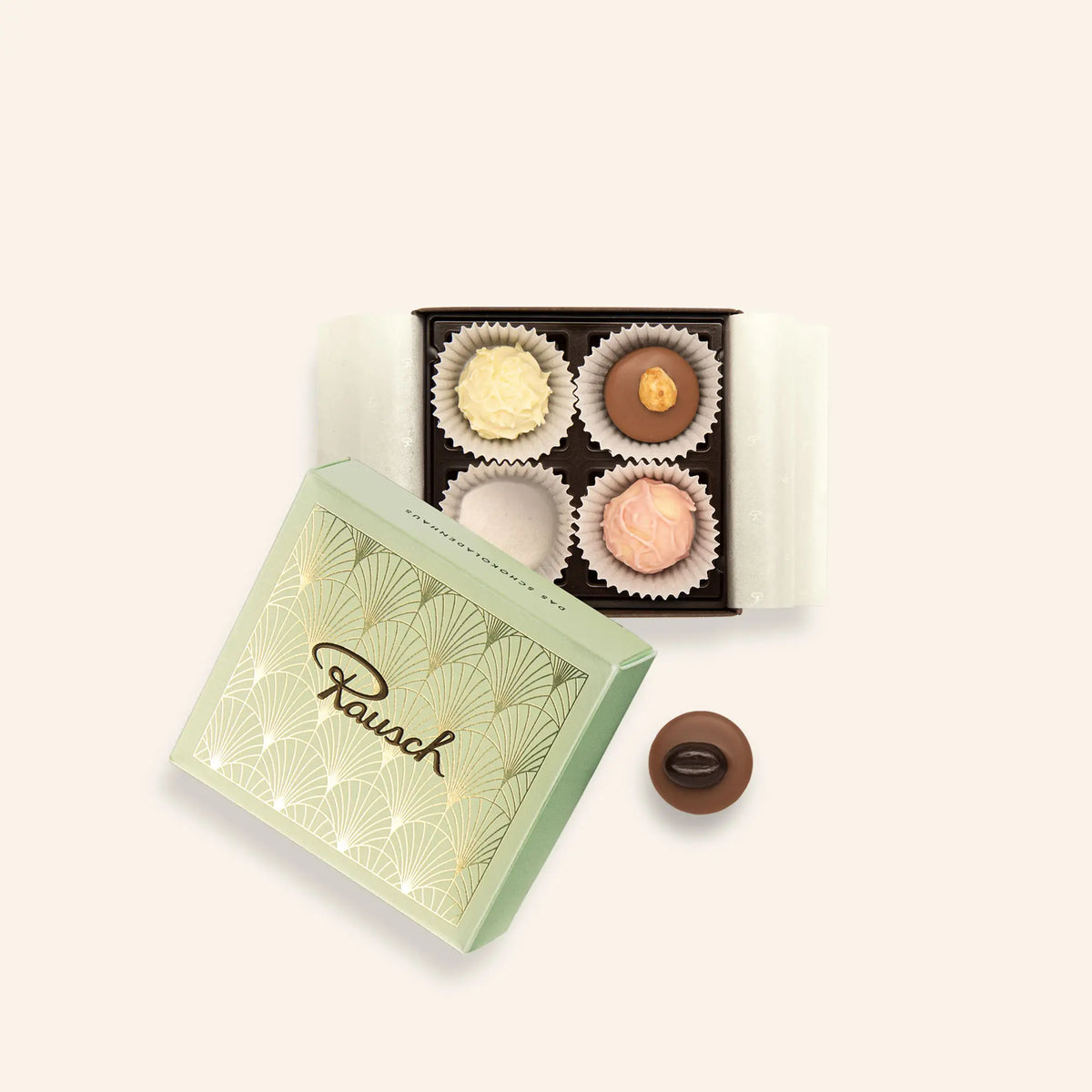 Elegante Rausch-Pralinenbox mit vier edlen Pralinen und mintgrüner Verpackung, eine Praline daneben platziert.