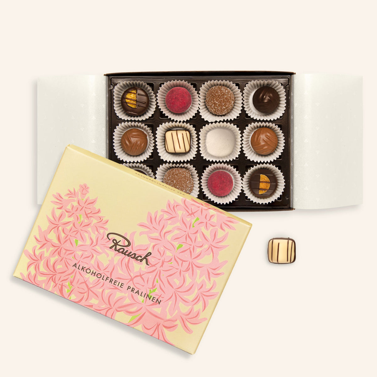 Offene Pralinenschachtel mit 12 alkoholfreien Pralinen, dekorative Verpackung mit rosafarbenem floralen Muster.