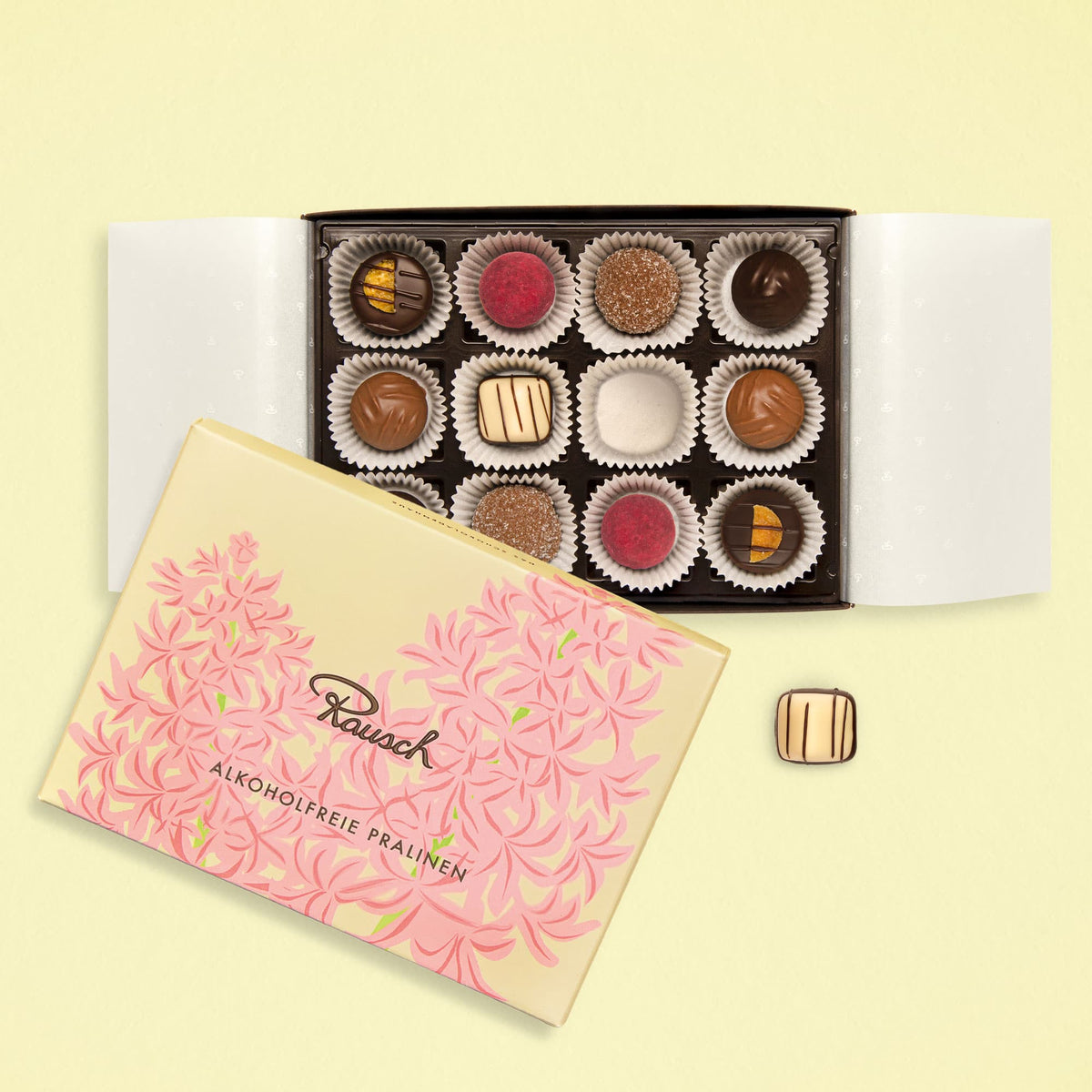 Elegante Pralinenschachtel mit 12 alkoholfreien Pralinen, dekoriert mit floralem Design, geöffnet auf hellem Hintergrund.