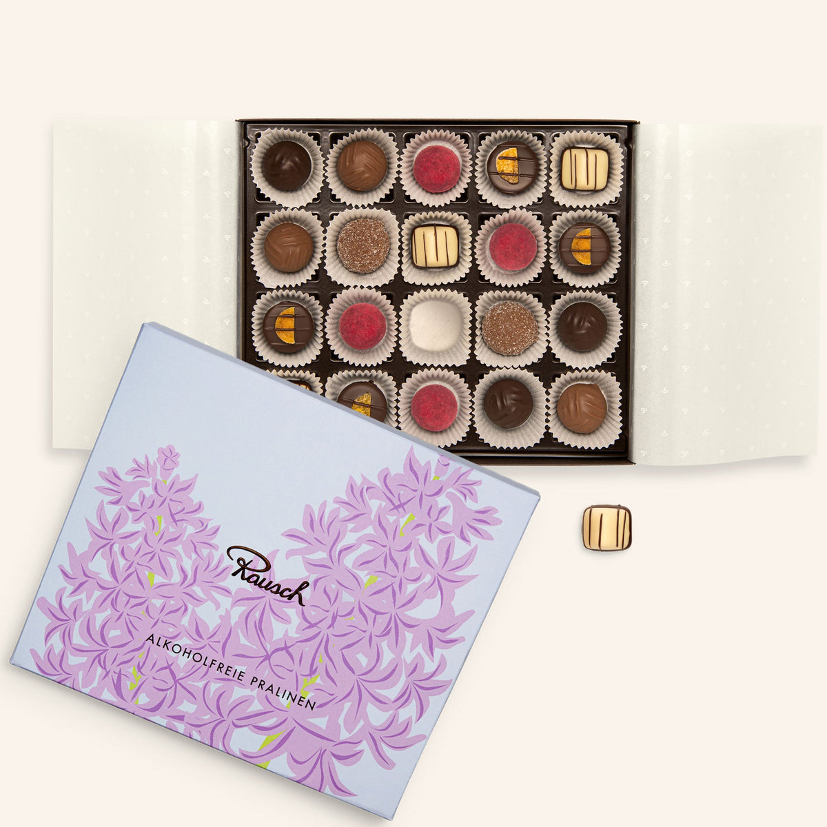 Offene Box mit 20 alkoholfreien Pralinen, lila Blumenmotiv auf dem Deckel, verschiedene Sorten sichtbar.