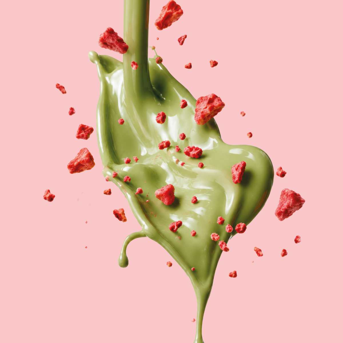 Grüne Matcha-Schokolade mit roten Erdbeerstückchen und cremiger Textur vor rosa Hintergrund. - Rausch