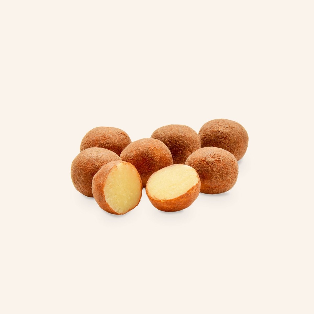 Mehrere Marzipankartoffeln auf hellem Hintergrund, eine halbiert, um das cremige Innere zu zeigen.