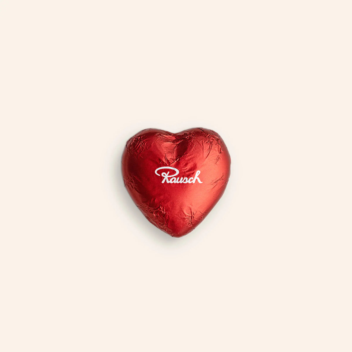 Rot eingepacktes Schokoladenherz mit Rausch-Logo auf hellem Hintergrund.