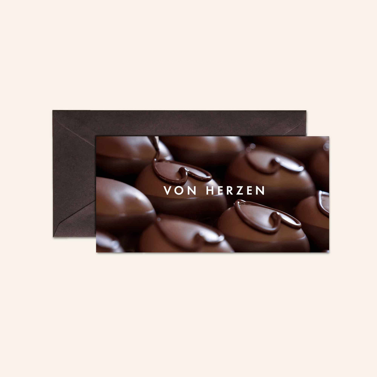 Grußkarte mit Schokoladenpralinen-Motiv und "Von Herzen" Schriftzug vor einem dunklen Umschlag.