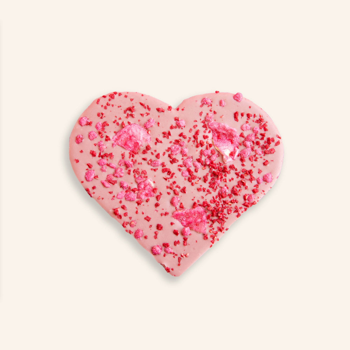 Herzförmige rosa Schokolade, bestreut mit roten Rosenblättern und Fruchtstückchen auf weißem Hintergrund.