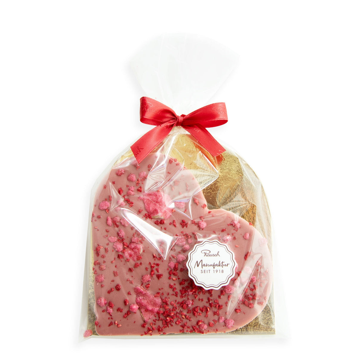 Herzförmige Ruby-Schokolade mit Rosenblättern, in Klarsichtfolie verpackt und roter Schleife verziert.