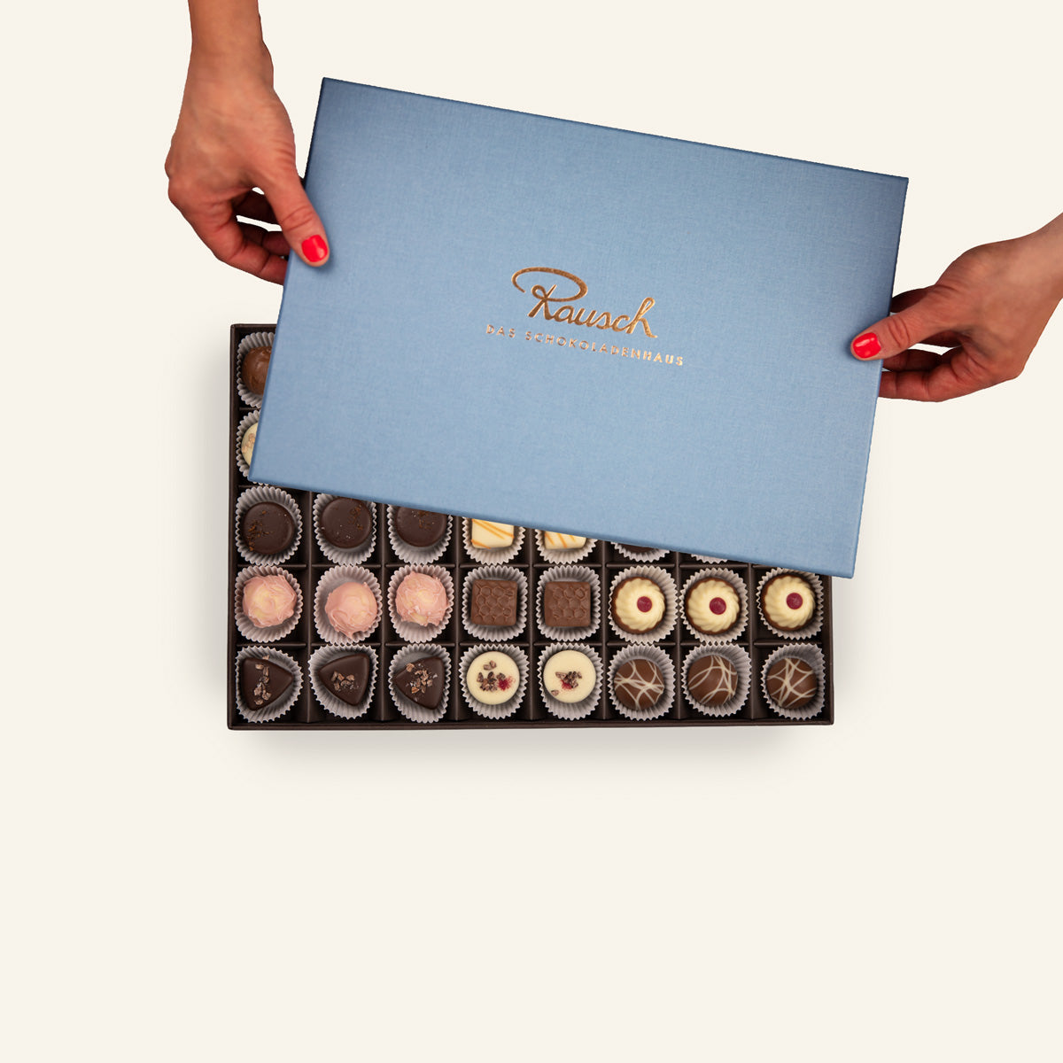 Eine offene Pralinenschachtel von Rausch, elegant verpackt, mit einer Auswahl an verschiedenen Pralinen.